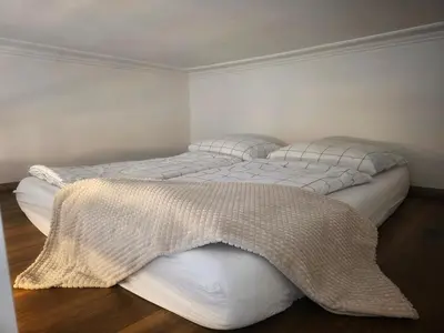 two beds with white sheets and a blanket on them at Small studio with loft bed in Prague