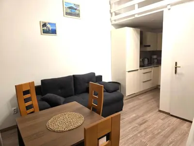 a living room with a table and a couch at Small studio with loft bed in Prague