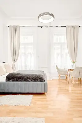a bedroom with a bed and a table and windows at Royal Apart in Prague