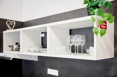 a white cabinet with wine glasses and plates at Royal Apart in Prague