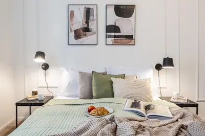 a bed with a book and a plate of food on it at Prague Days - Two Bedroom Apartment with Parking and Netflix in Karlín in Prague