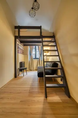 a loft bed in a room with a couch and a bunk bed at KYRA Apartments by Rentez in Prague