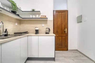 a kitchen with white cabinets and a wooden door at KYRA Apartments by Rentez in Prague