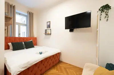 a bedroom with a large bed with a television on the wall at Little Oasis in Prague