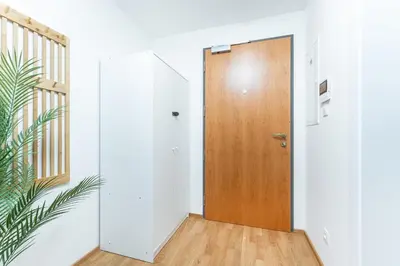 a wooden door in a white room with a staircase at Rentero NEW Anděl Skyline Apartment - Prague 5 in Prague