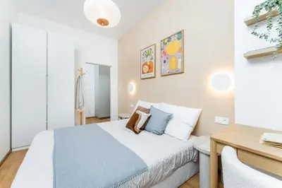 a white bedroom with a bed and a desk at Rentero NEW Anděl Skyline Apartment - Prague 5 in Prague