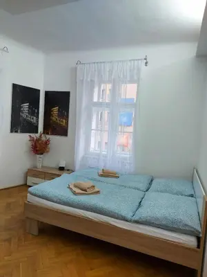a bedroom with a bed with blue sheets and a window at Sophia apartment in Prague
