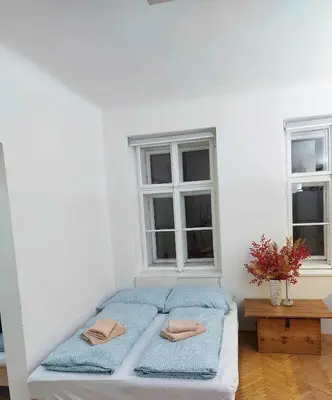 a white room with a bed with two windows at Sophia apartment in Prague