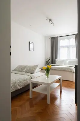 a dining table with two chairs and a vase with red flowers at Cozy One-Bedroom Apartment by Flora Metro Station in Prague