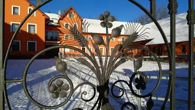 a view of a house in the snow through a gate at Podřipská Farma in Roudnice nad Labem