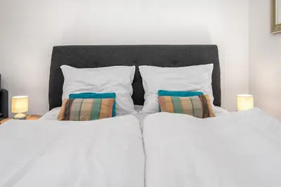 a bedroom with two beds with white sheets and two pillows at Serenity Suite Prague in Prague