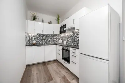 a white kitchen with white cabinets and a refrigerator at Serenity Suite Prague in Prague
