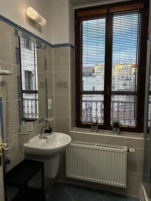 a bathroom with a sink and two windows and a toilet at Balbinova Grand Apartment Private Balcony in Prague