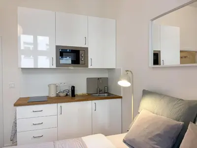 a kitchen with white cabinets and a bed in a room at Museum Park Apartment II in Prague