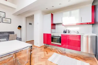 a kitchen with red cabinets and a wooden floor at Rooftop Apartment, Vinohrady, City Center in Prague