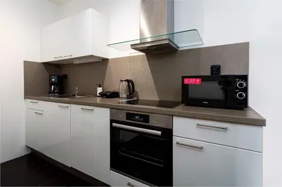 a kitchen with white cabinets and a black microwave at Crown Tiger Penthouse in Prague