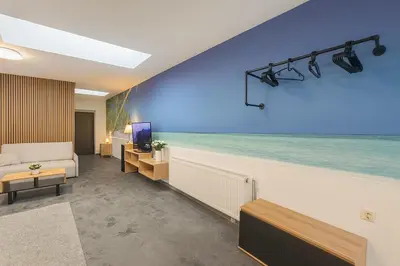 a room with a blue wall with a bed and a television at Ideal for Big Groups, Modern 14 Guest Apartment Near Prague in Rakovník