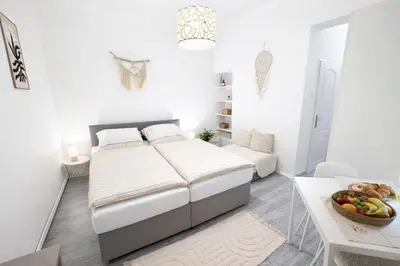 a white bedroom with a bed and a table with a bowl of fruit at D&D Apartment Moderní apartmán v centru Prahy in Prague