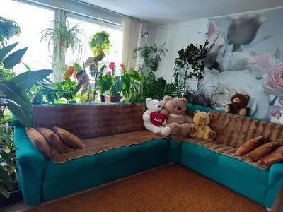a couch with stuffed animals on it in a room with plants at Оазис in Jíloviště