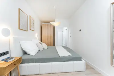 a white bedroom with a bed and a desk at Rentero Riverside Serenity Residence - Prague 7 in Prague