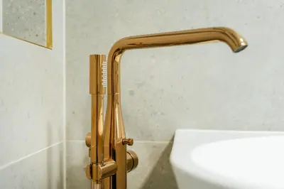 a brass faucet over a toilet in a bathroom at Rentero Riverside Serenity Residence - Prague 7 in Prague