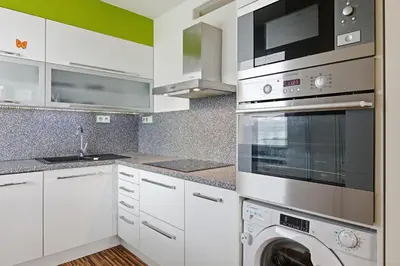 a kitchen with white cabinets and a washer and dryer at Apartment in a quiet part of Prague with a kitchen in Prague