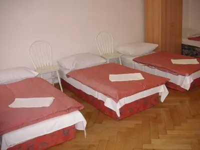 three beds in a room with red and white covers at Hostel Bell in Prague
