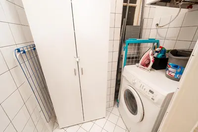 a washer and dryer in a white tiled bathroom at Charming Apartment in Haštalská in Prague