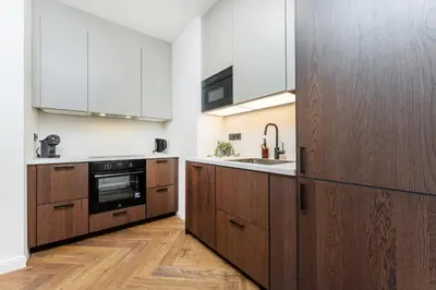a kitchen with wooden cabinets and a sink at Rentero Urban Elegance Suite - Prague 7 in Prague
