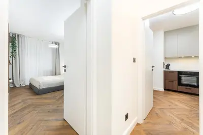a white room with a bed and a kitchen at Rentero Urban Elegance Suite - Prague 7 in Prague