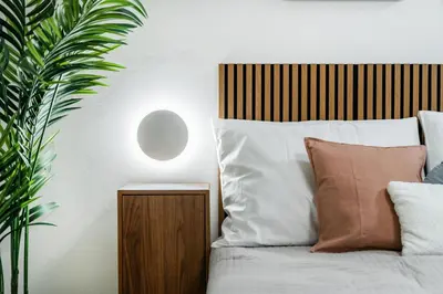 a bed with a wooden headboard next to a plant at Rentero Urban Elegance Suite - Prague 7 in Prague