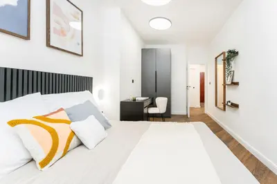 a bedroom with a white bed and a desk at Rentero Urban Elegance Suite - Prague 7 in Prague