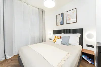 a bedroom with a large white bed and a window at Rentero Urban Elegance Suite - Prague 7 in Prague