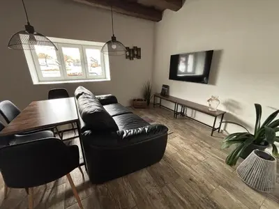 a living room with a black leather couch and a table at Retreat House Na návsi in Chotěšov