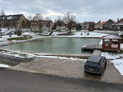 a car parked in front of a pond in the snow at Retreat House Na návsi in Chotěšov
