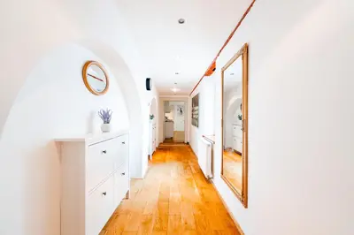 a hallway with white walls and wood floors and a mirror at Huge 4 Rooms Charles Bridge Apartment in Prague