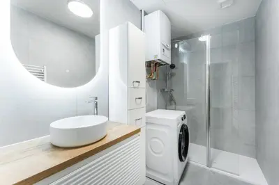 a bathroom with a sink and a washing machine at Rentero Smíchov Riverside & Station Residence in Prague