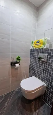 a bathroom with a toilet and a tiled wall at Garden Residence - Byt 412 in Prague