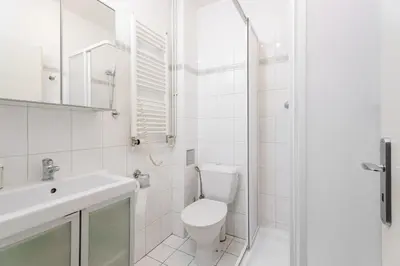 a white bathroom with a toilet and a sink at Quiet Apartment Near River and City Center in Prague