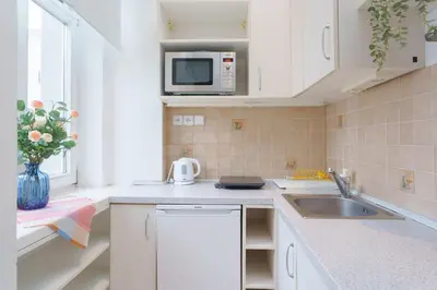 a white kitchen with a sink and a microwave at Quiet Apartment Near River and City Center in Prague