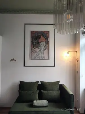 a living room with a green couch and a picture on the wall at Alphonse Mucha Loft Apartments, Prague 2 in Prague