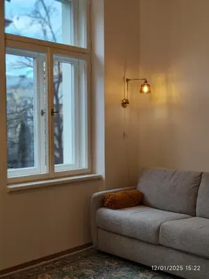 a living room with a couch and two windows at Alphonse Mucha Loft Apartments, Prague 2 in Prague