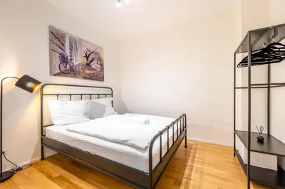 a bedroom with a bed with white sheets and a lamp at William's Modern Luxe Suite by the Station in Prague