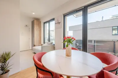 a dining room with a white table and red chairs at William's Modern Luxe Suite by the Station in Prague