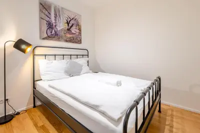 a bed with white sheets and a lamp in a room at William's Modern Luxe Suite by the Station in Prague