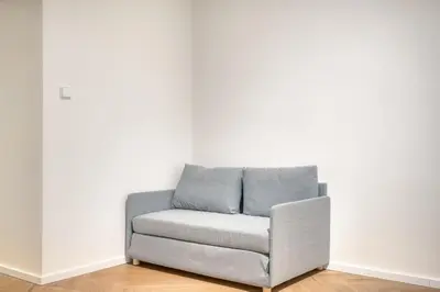 a grey chair in a room with a white wall at Modern City Apartment with Balcony by Rentez in Prague