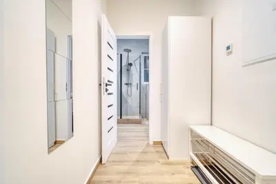 a hallway with white walls and a walk in shower at Modern City Apartment with Balcony by Rentez in Prague