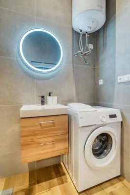 a bathroom with a washing machine and a sink at Modern City Apartment with Balcony by Rentez in Prague