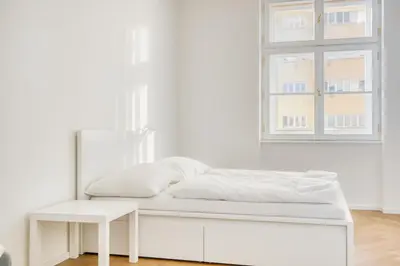 a white bedroom with a bed and a window at Modern City Apartment with Balcony by Rentez in Prague