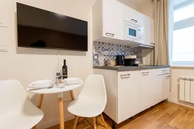a kitchen with white cabinets and a small table and chairs at ZEN APT Prague 1 City Center Modern Studio in Prague